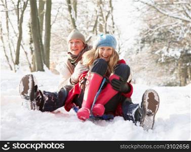 Couple Sledging Through Snowy Woodland