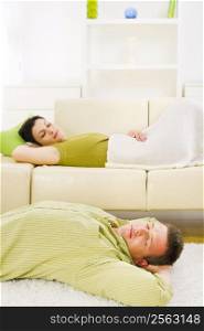 Couple sleeping at home on sofa and on floor.