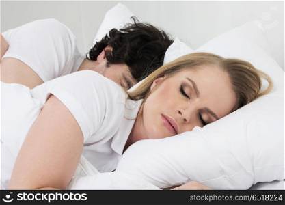 Couple sleeping in bed. Young couple sleeping in bed with white blanket and pillows