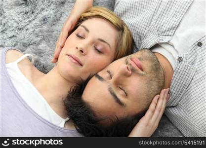 Couple sleeping on gray carpet