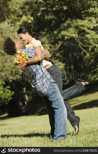 Couple smiling and embracing in park.