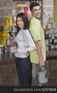 Couple smiling and holding paint cans in a hardware store