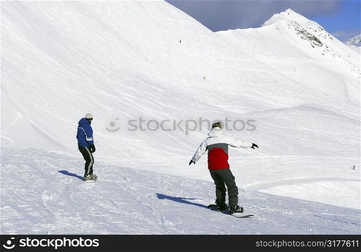 Couple snowboarding on the backdrop of scenic view in Canadian Rocky mountains ski resort