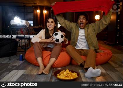 Couple soccer fan watching football match on home TV projector cheering for favorite team. Couple watching football match on home projector