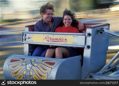 Couple spinning in amusement park ride