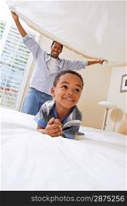Couple Spreading Bedsheet Over Son