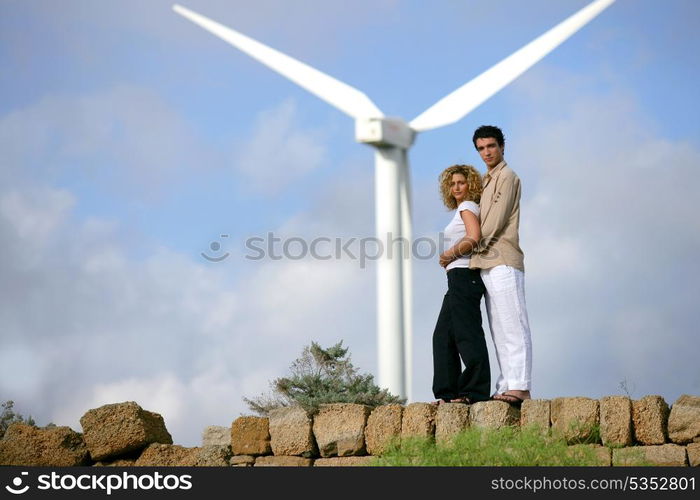 Couple standing before a wind turbine