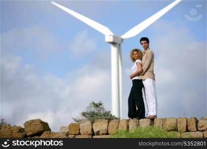 Couple standing before a wind turbine