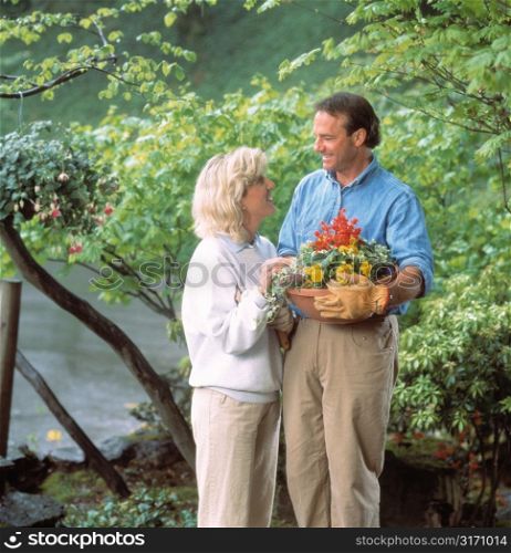 Couple Standing in Garden With Pot of Flowers