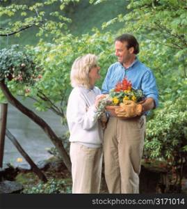 Couple Standing in Garden With Pot of Flowers