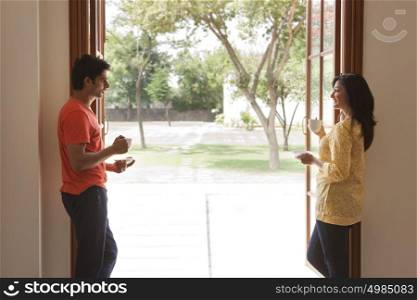 Couple standing inside house having coffee