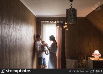 couple standing near window playing with their baby home
