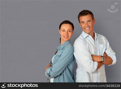 Couple standing on grey background with arms crossed