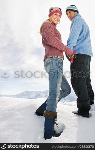 Couple standing on snow covered hill portrait low angle view