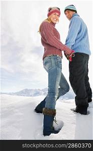 Couple standing on snow covered hill portrait low angle view