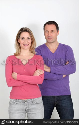 Couple standing on white background with arms crossed