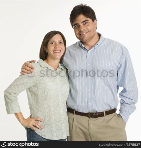 Couple standing smiling against white background.