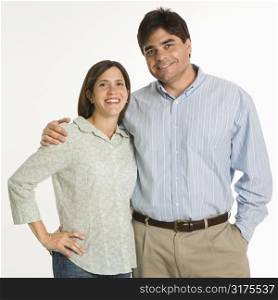 Couple standing smiling against white background.