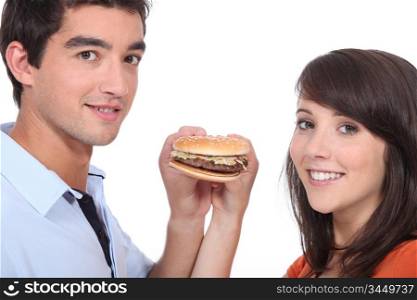 Couple stood holding a cheeseburger
