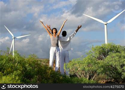 Couple stretching near wind turbines
