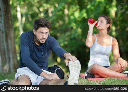 couple stretching outdoors while drinking water