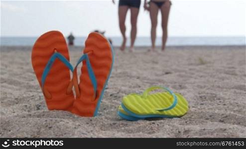 Couple summer beach vacation getaway flip flops in the sand male and female legs in the background