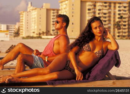 Couple sunbathing on beach, Miami, Florida