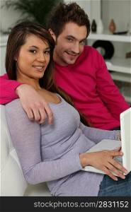 Couple surfing the internet together in the sofa