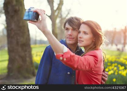 Couple taking camera selfie in park, London, UK