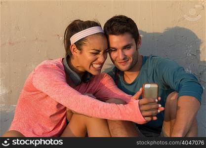 Couple taking selfie in front of concrete wall