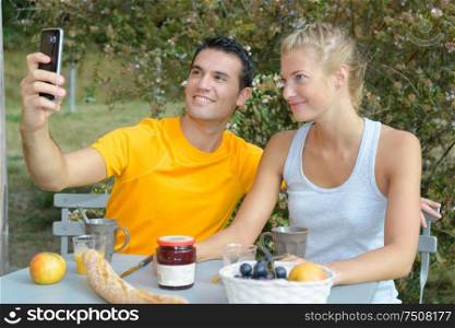 Couple taking selfie while eating breakfast outdoors