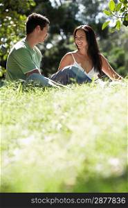 Couple talking together other sitting on grass ground view