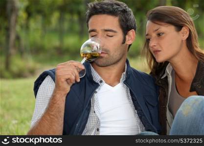 Couple tasting wine in field
