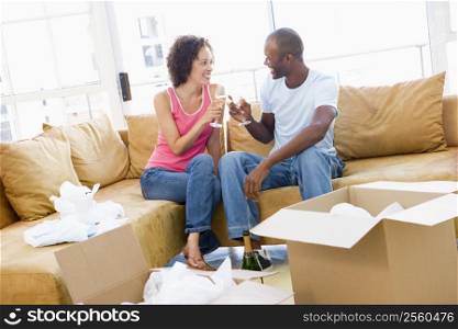 Couple toasting champagne by boxes in new home smiling