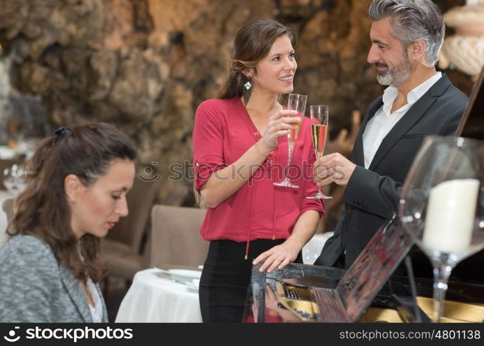 Couple toasting champagne, serenaded by pianist