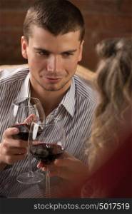 Couple toasting wine glasses while sitting at restaurant and having romantic date