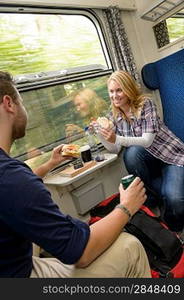 Couple traveling by train eating sandwiches hungry smiling woman man