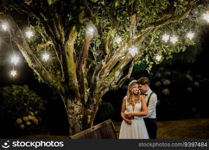 Couple under a tree with pendant lights on their wedding day. KEILA   RUB 