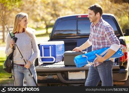 Couple Unpacking Pick Up Truck On Camping Holiday