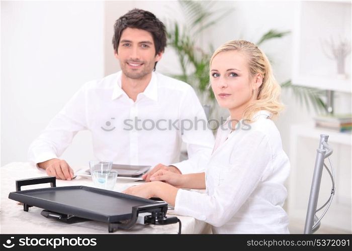 Couple using an electric tabletop hotplate