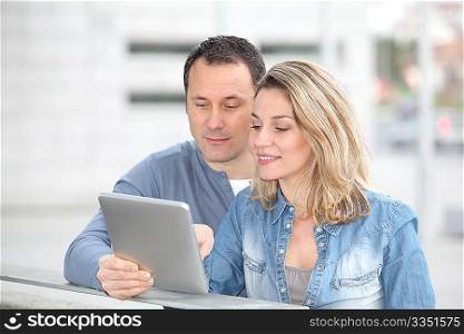 Couple using electronic tab in the street