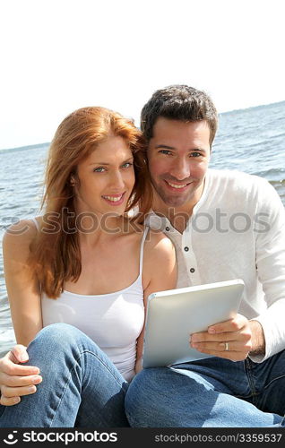 Couple using electronic tablet by a lake