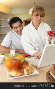 Couple using laptop at breakfast