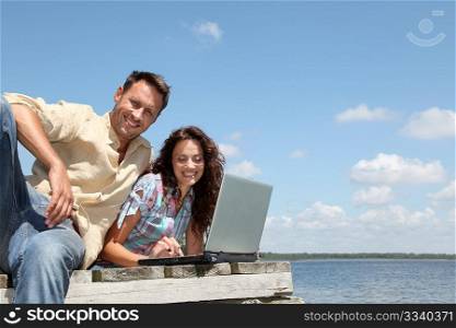 couple using laptop computer on a pontoon