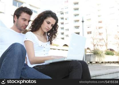 Couple using laptop computer outdoors
