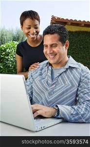 Couple using laptop in back yard