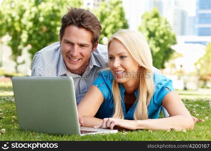 Couple using laptop in city park