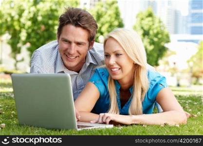 Couple using laptop in city park
