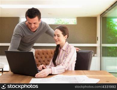 Couple using laptop in home office