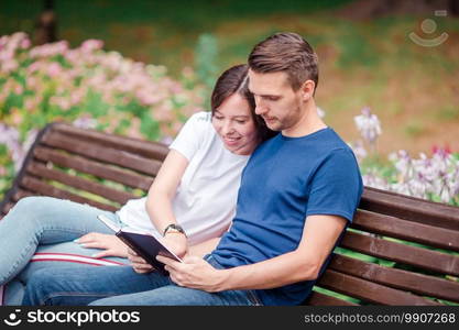 Couple using tablet and cellphone in public park. Family listening to music using headphones. Couple using tablet and cellphone in public park.